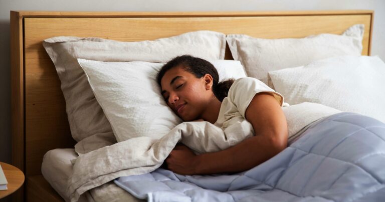 A person sleeping soundly on white pillows in a wooden bed