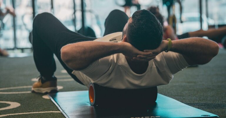 A person using a foam roller on their upper back on a gym floor