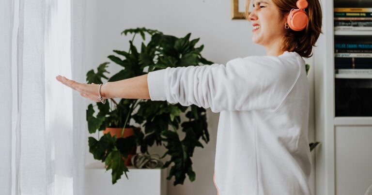 A person standing at their desk stretching both arms out to the side