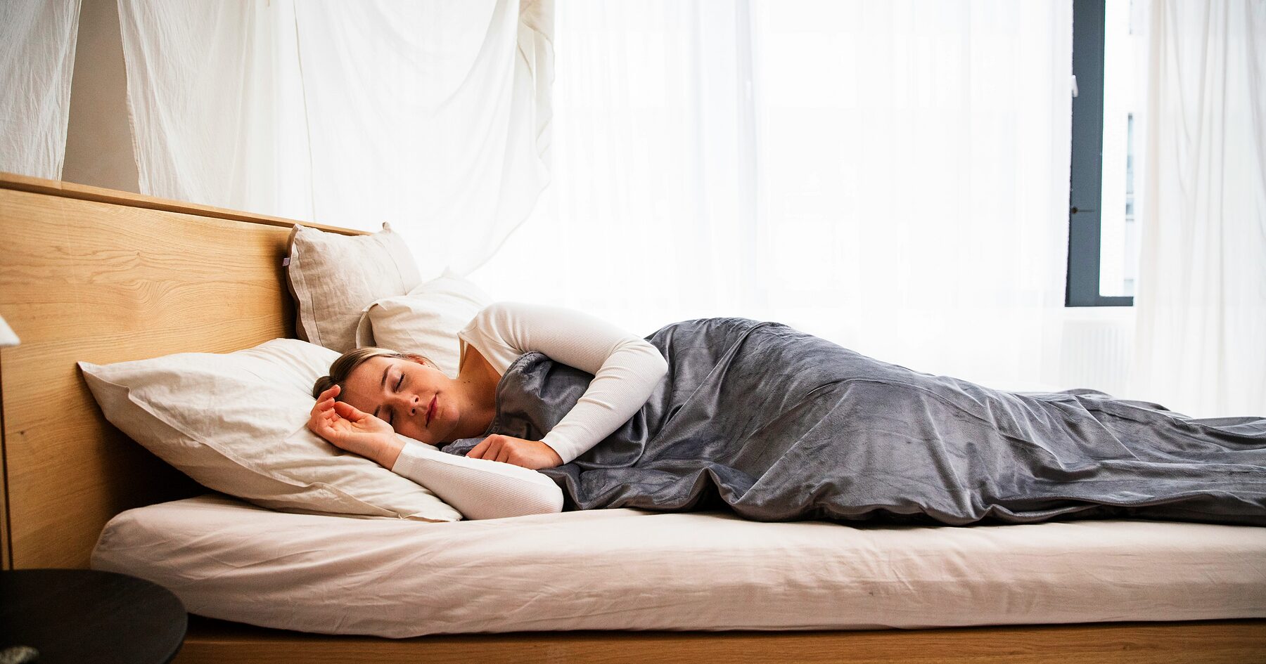 Person asleep on their side in a bed with grey bedding