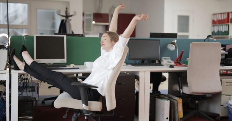 A person stretching their arms overhead in an office chair